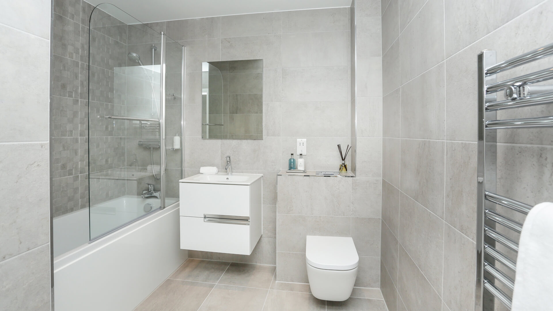 Bathroom with grey tiling, white toilet, mirror and sink