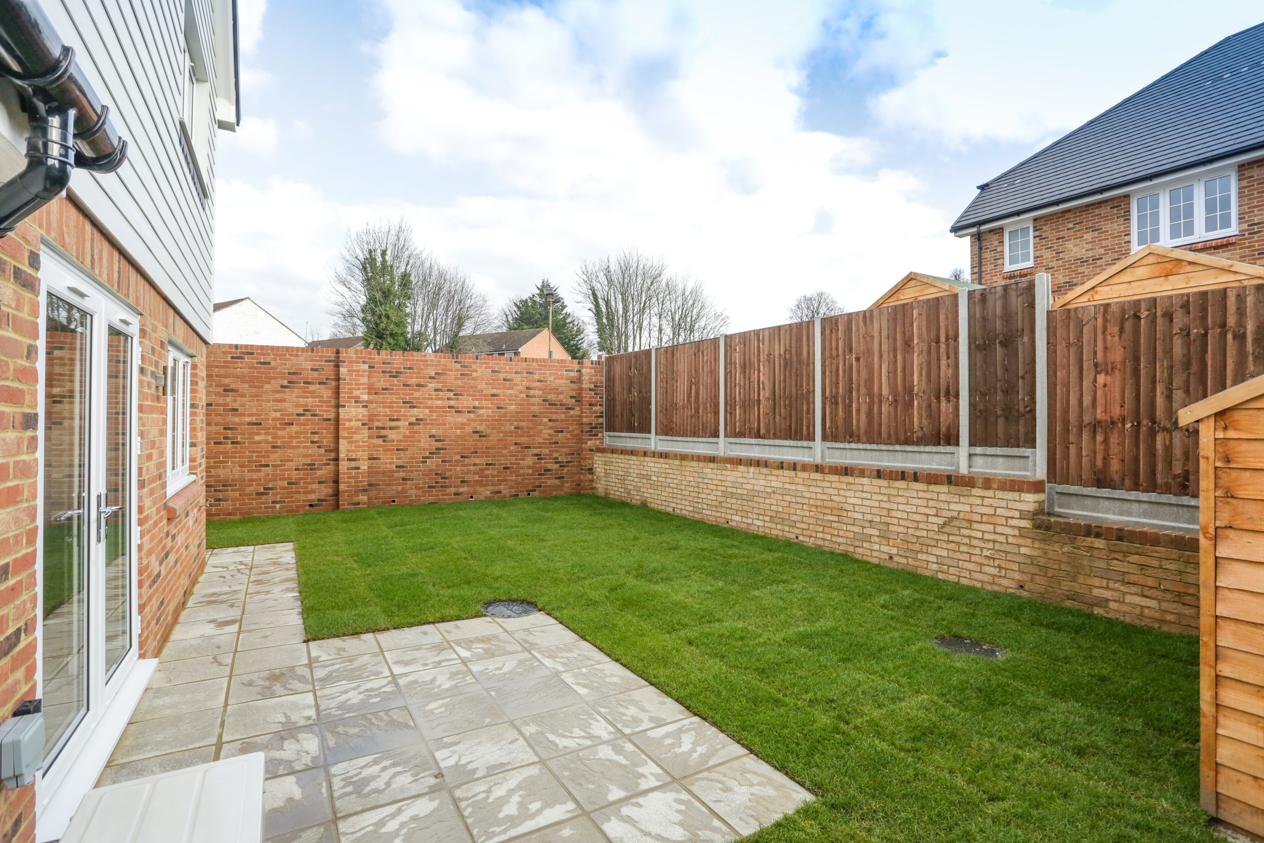 Garden at our Ivy Court development with grass and tiling and shed.