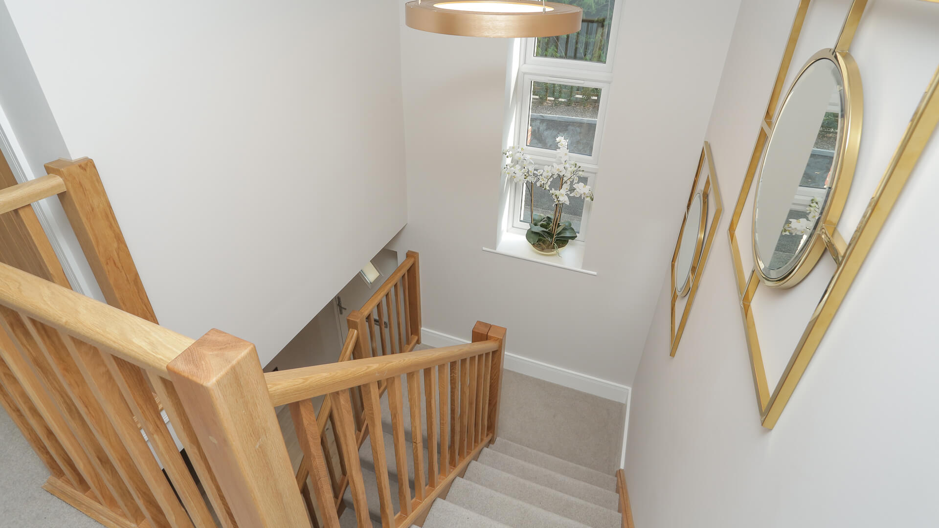 Stairwell with oak banister and beige carpet at Woodside cour.