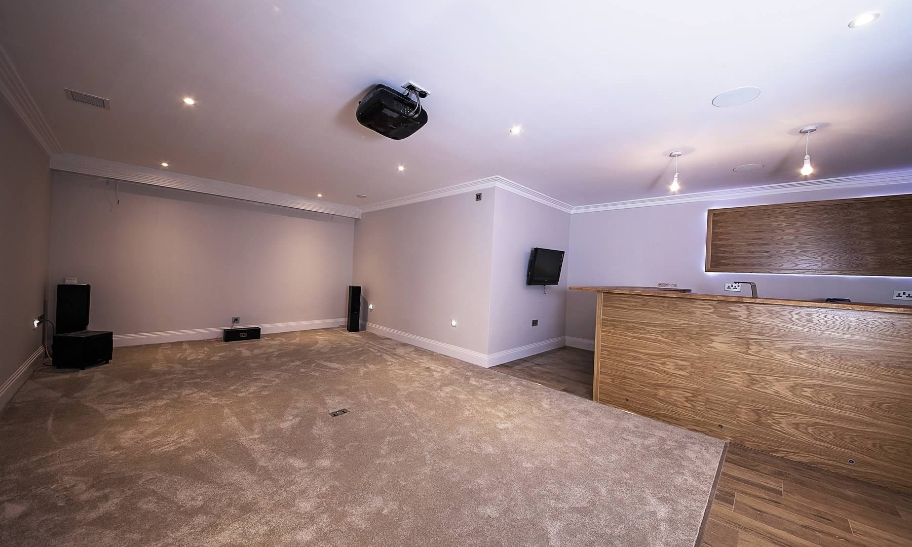 Spacious empty room with carpet and surround sound speakers.