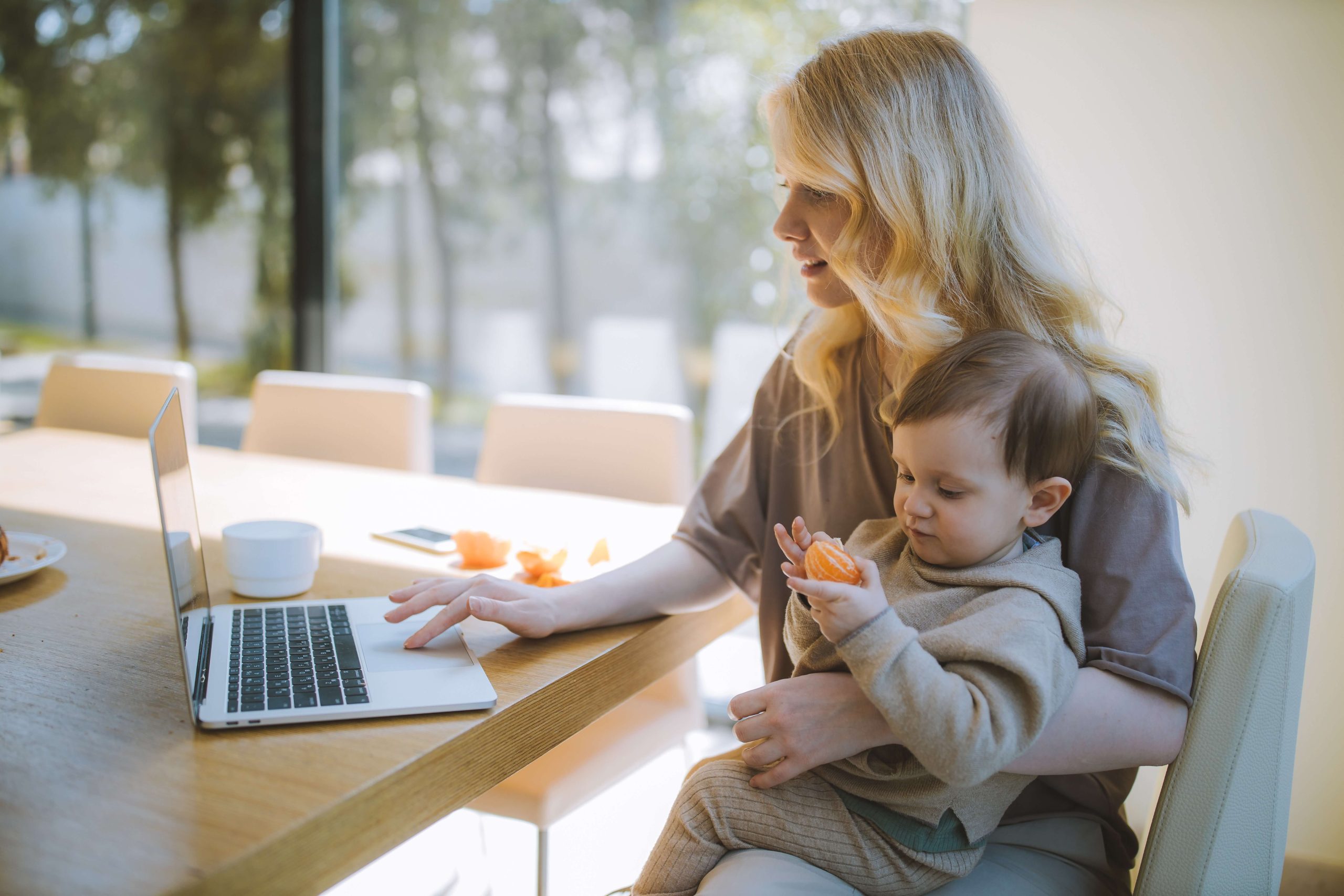 Woman with a baby on her lap looking at virtual house tours online