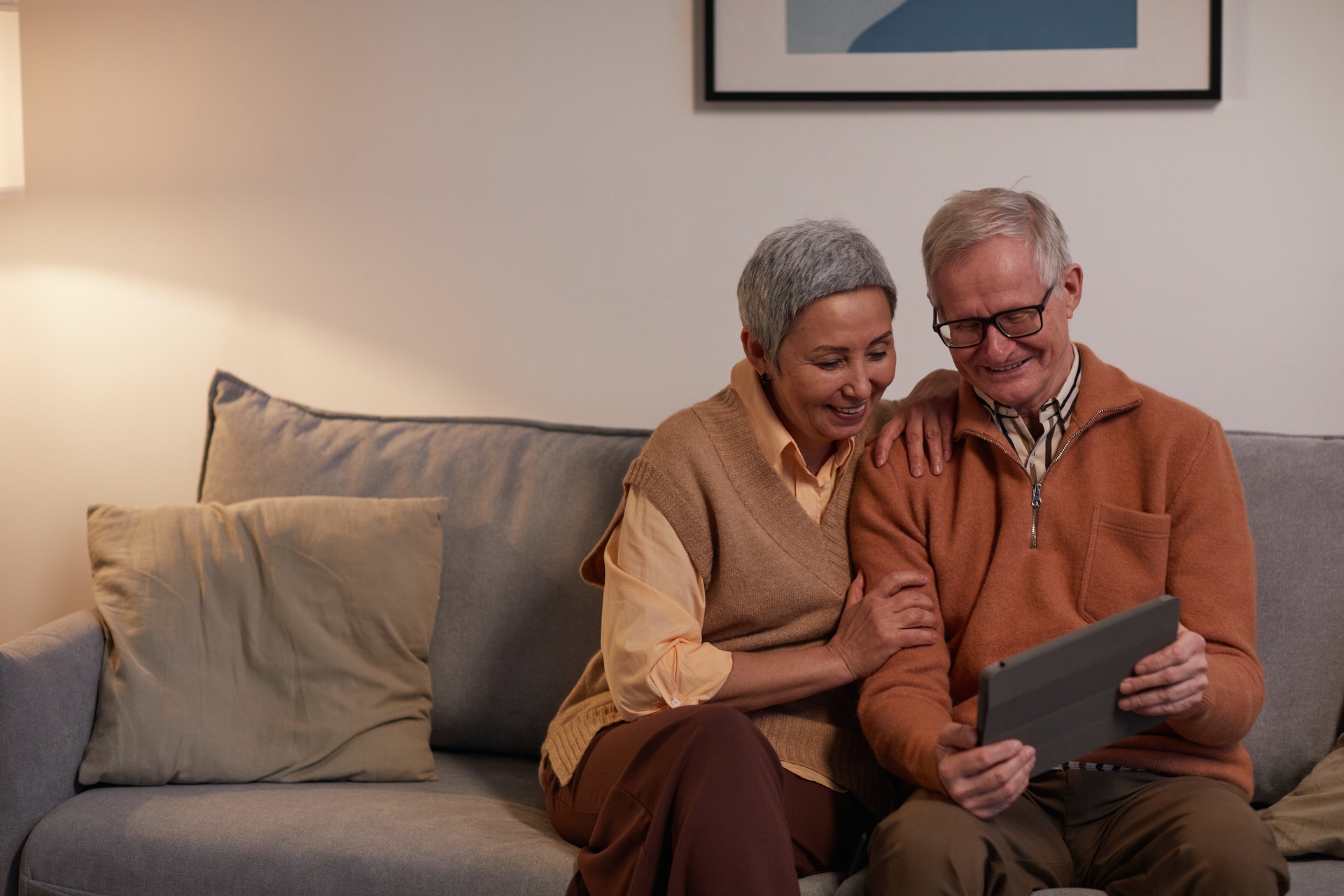 Elderly couple on tablet on a sofa